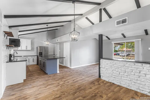 a view of a kitchen with a sink wooden cabinets and stainless steel appliances