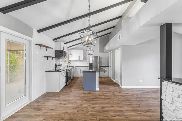 a kitchen with stainless steel appliances kitchen island granite countertop a refrigerator and a stove top oven