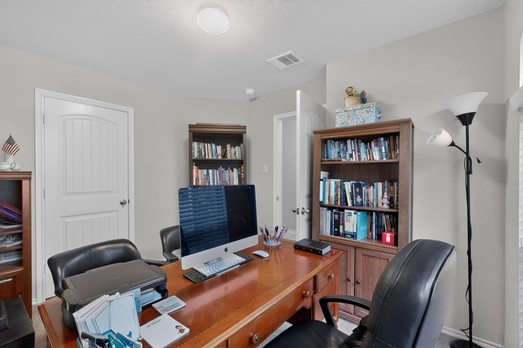 1409 Slate Street Princeton, TX 75407 - Photo 29 of 36 Dedicated workspace featuring light gray walls, a built-in wooden desk, and two freestanding wooden bookshelves