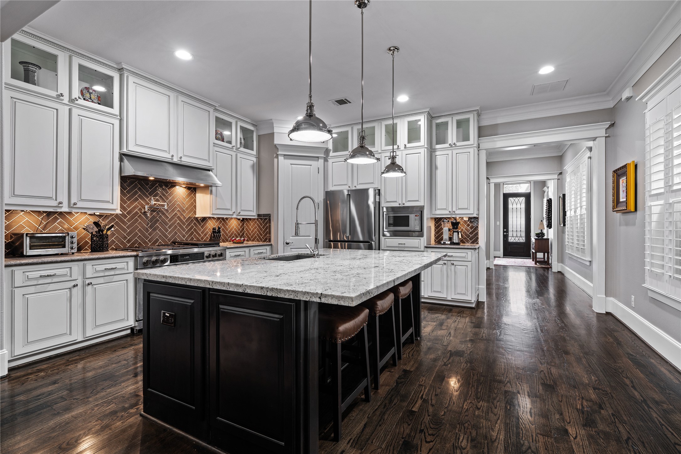 422 West 26th Street Houston, TX 77008 - Photo 12 of 39 Looking back toward the entry, the kitchen’s generous scale is highlighted by decorative glass-front cabinetry and sleek pendant lighting.