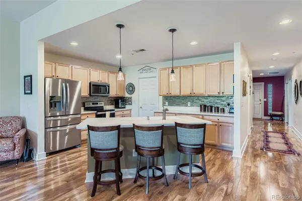 a kitchen with stainless steel appliances granite countertop a refrigerator a stove top oven a sink dishwasher and white cabinets with wooden floor