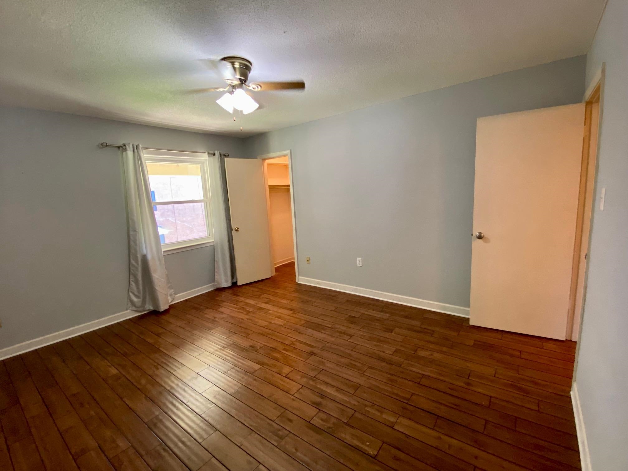 5700 Quince Road, Unit 4 Memphis, TN 38119 - Photo 9 of 16 a view of an empty room with wooden floor and a window