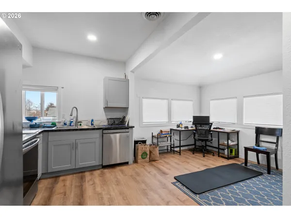 a kitchen with stainless steel appliances granite countertop a stove top oven a sink a dining table and chairs with wooden floor