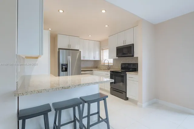 a kitchen with kitchen island a refrigerator stove microwave and cabinets