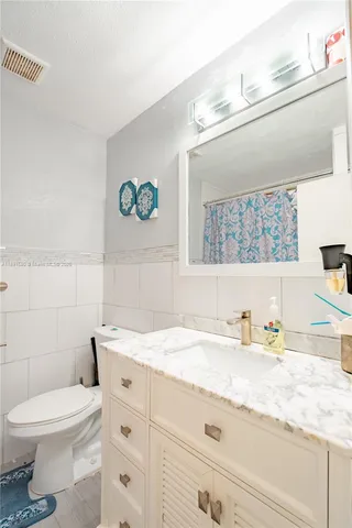 a bathroom with a granite countertop toilet sink and mirror