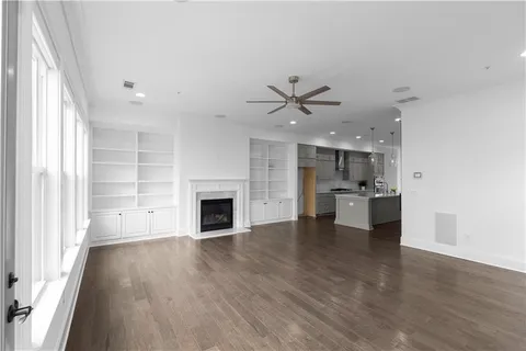 a view of a big room with wooden floor a kitchen view and a fireplace