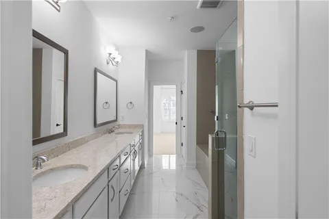 a bathroom with a granite countertop double vanity sink a mirror and a shower