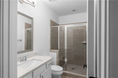 a bathroom with a shower sink vanity mirror and toilet