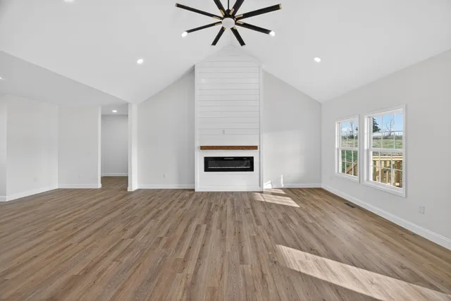 a view of an empty room with a window and wooden floor