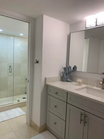 a bathroom with a shower sink vanity granite and mirror