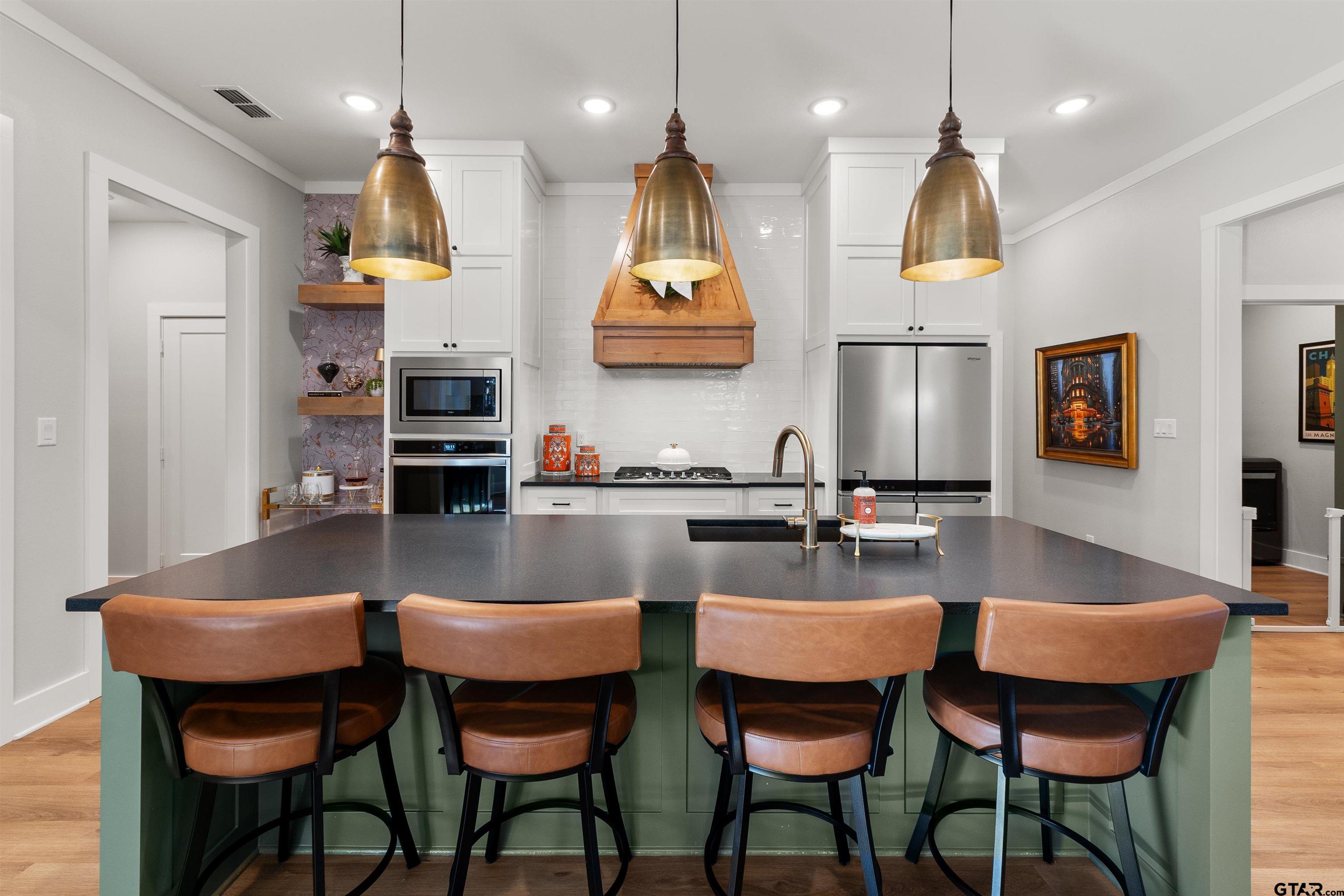 a kitchen with stainless steel appliances granite countertop a kitchen island a table and chairs