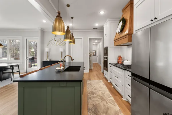 a kitchen with stainless steel appliances granite countertop a sink dishwasher a refrigerator and cabinets with wooden floor