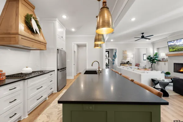 a kitchen with stainless steel appliances granite countertop a sink dishwasher and a refrigerator with wooden floor