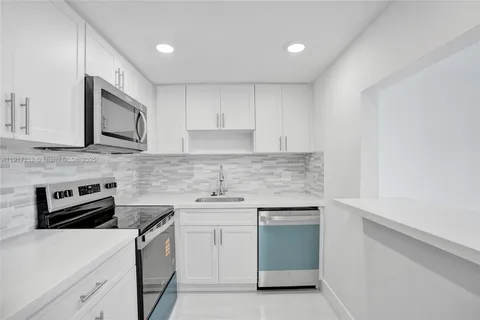 a kitchen with white cabinets stainless steel appliances and sink
