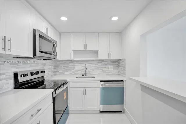 a kitchen with white cabinets stainless steel appliances and sink
