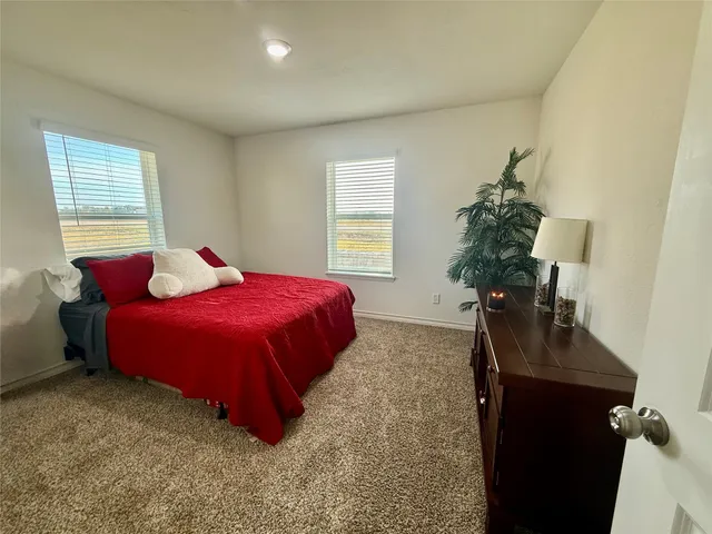 a bedroom with a bed and a potted plant on the dresser