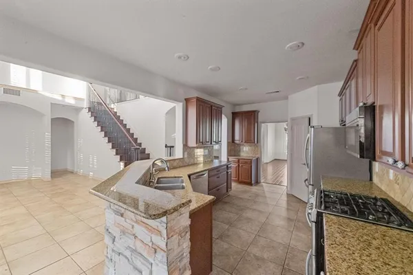 a kitchen with stainless steel appliances granite countertop a stove a sink and a refrigerator