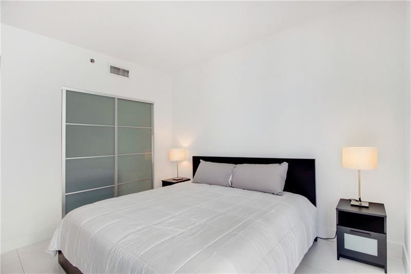 1050 Brickell Avenue, Unit 3222 Miami, FL 33131 - Photo 6 of 12 a bedroom with a bed and a lamp