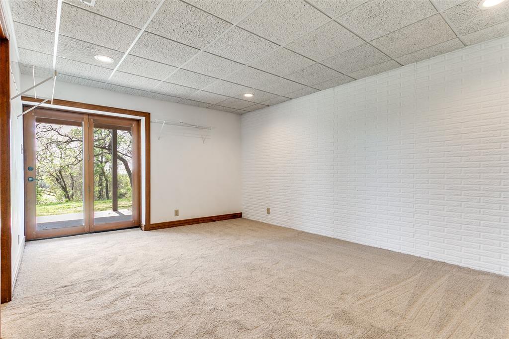 1557 Latigo Hills Road Bartonville, TX 75022 - Photo 28 of 40 Empty room with brick wall, light carpet, a paneled ceiling, and recessed lighting