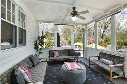 a view of a patio with couches table and chairs under an umbrella with wooden floor
