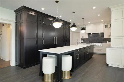 a large kitchen with stainless steel appliances kitchen island granite countertop a stove a sink and a refrigerator