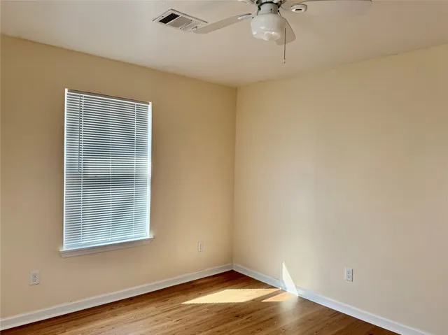 a view of an empty room with a window and wooden floor