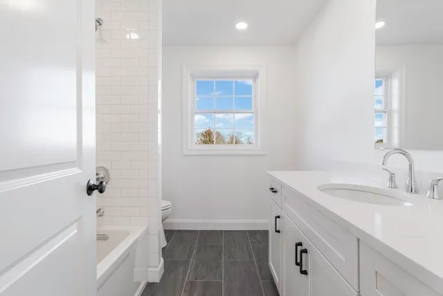 a bathroom with a tub sink toilet and a mirror