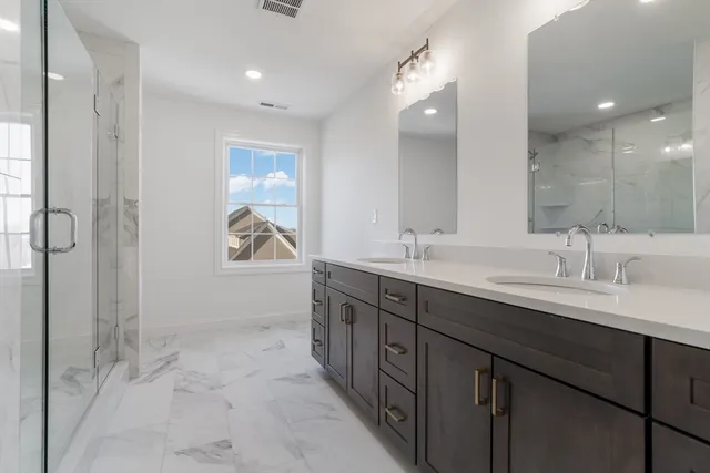 a bathroom with a double vanity sink a mirror and a shower