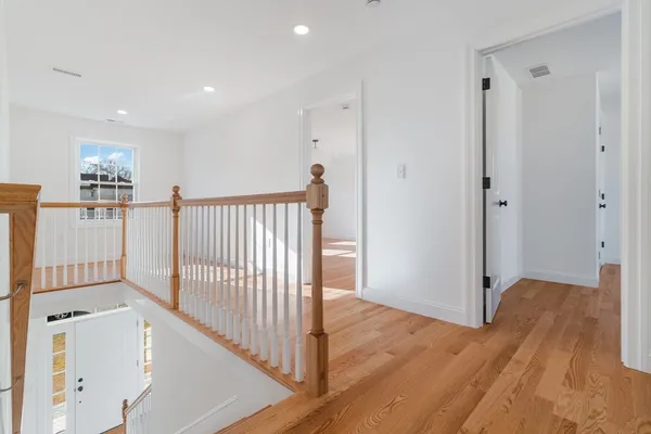 a view of a hallway with entryway and wooden floor