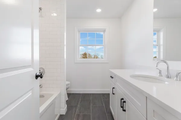 a bathroom with a tub sink toilet and a mirror