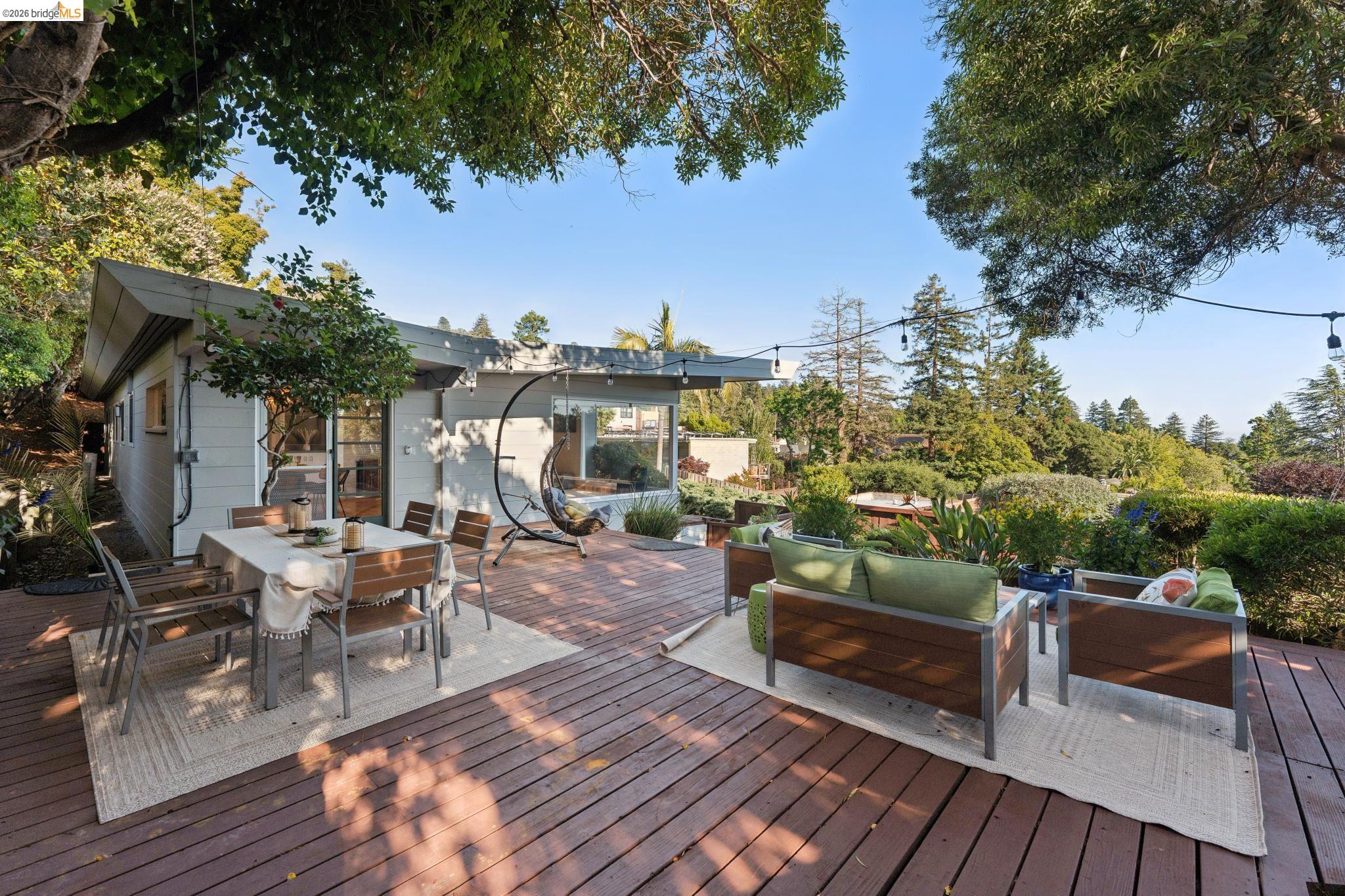 2301 Oak Street Berkeley, CA 94708 - Photo 33 of 61 Expansive wood deck featuring a light gray exterior, string lighting, and extensive surrounding foliage