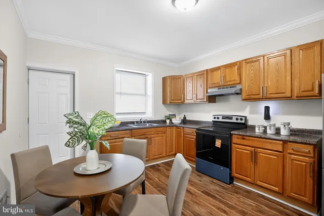 a kitchen with stainless steel appliances a refrigerator a stove a sink dishwasher and a dining table with wooden floor