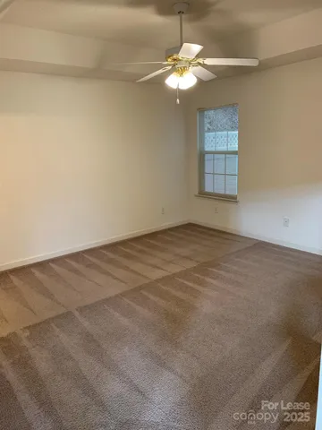 an empty room with a chandelier fan and windows