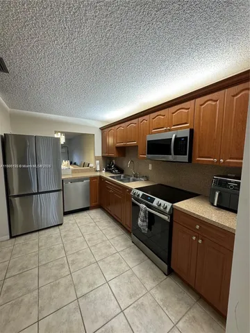 a kitchen with stainless steel appliances granite countertop a stove top oven a sink and a refrigerator