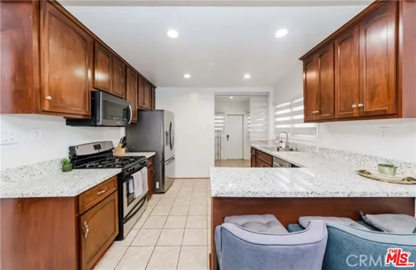 a kitchen with granite countertop stainless steel appliances a sink a stove top oven a counter space and cabinets