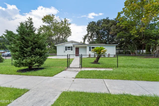 a backyard of a house with table and chairs plants and large tree