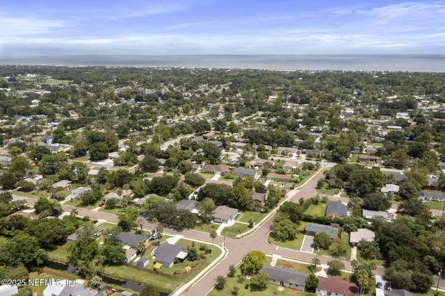 a view of a white house with a big yard plants and large trees