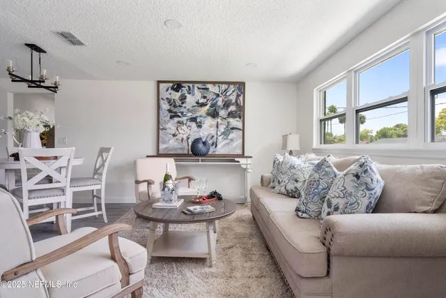a living room with stainless steel appliances furniture a dining table and a chandelier