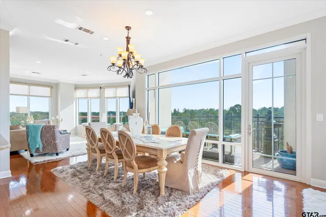 a dining room with wooden floor a chandelier a glass table and chairs