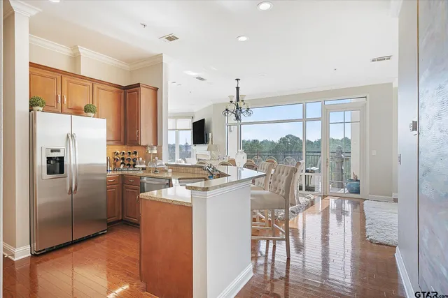 a kitchen with a refrigerator a stove and a view of living room