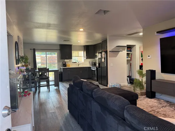 a living room with stainless steel appliances kitchen island granite countertop furniture wooden floor and a view of kitchen