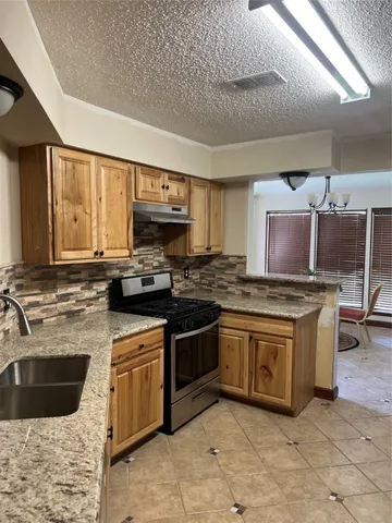 a kitchen with stainless steel appliances granite countertop a stove a sink and a microwave
