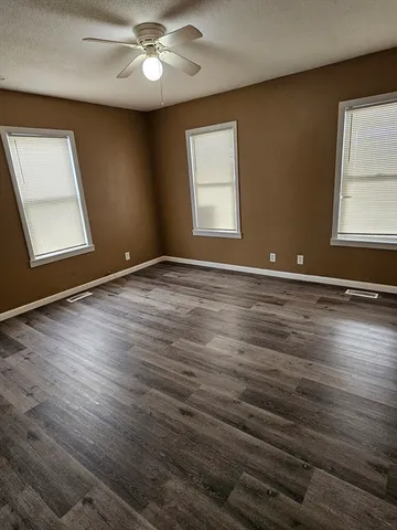 a view of an empty room with window and wooden floor