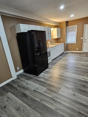 a kitchen with granite countertop white cabinets and refrigerator