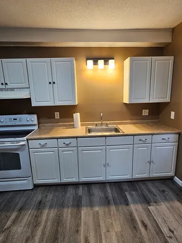 a kitchen with granite countertop cabinets stainless steel appliances a sink and a window