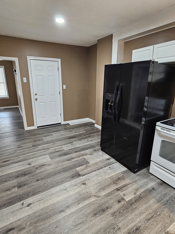 176 Corthell Street, Unit 1 Springfield, MA 01151 - Photo 19 of 28 a view of a refrigerator in kitchen and an empty room with wooden floor