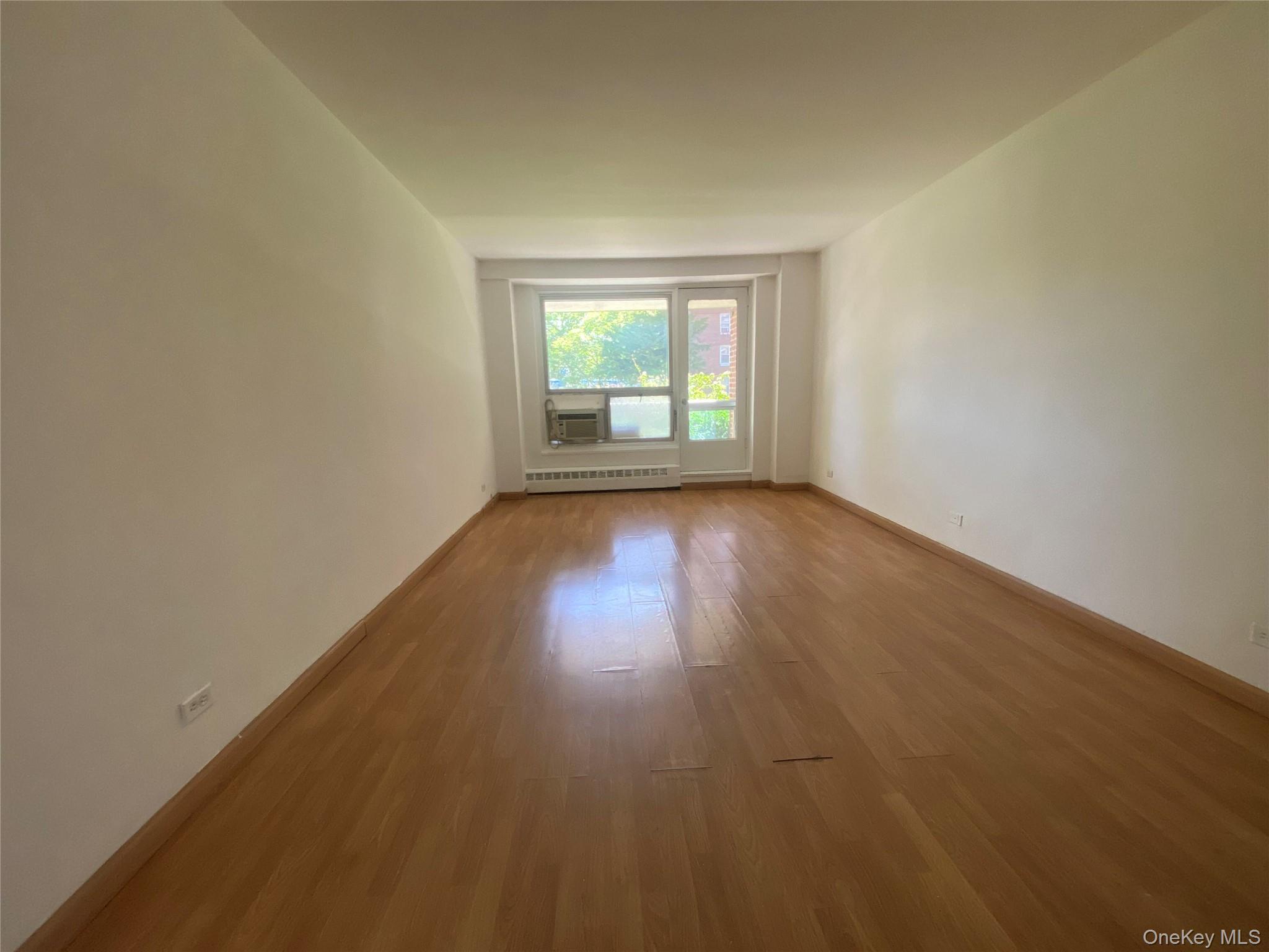 98-05 63rd Road, Unit 1C Queens, NY 11374 - Photo 2 of 5 Empty room featuring wood finished floors and baseboards