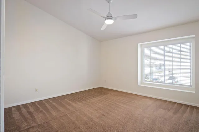 an empty room with a window and ceiling fan