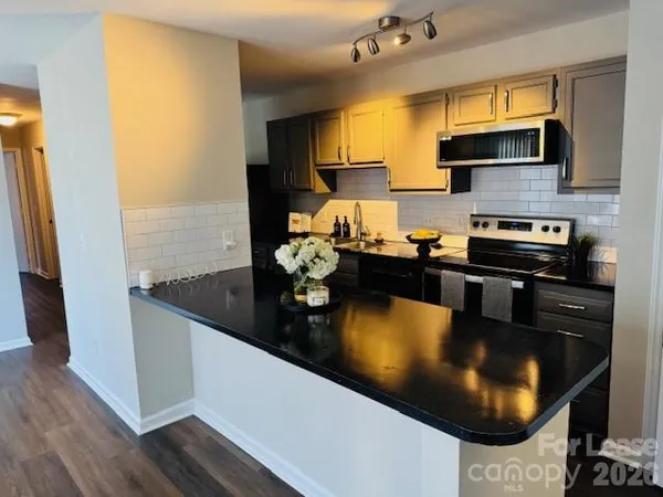 a kitchen with microwave a stove and cabinets