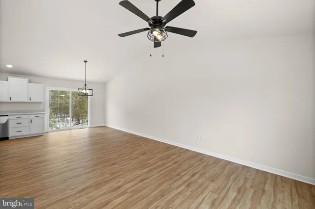 a view of an empty room with window and wooden floor